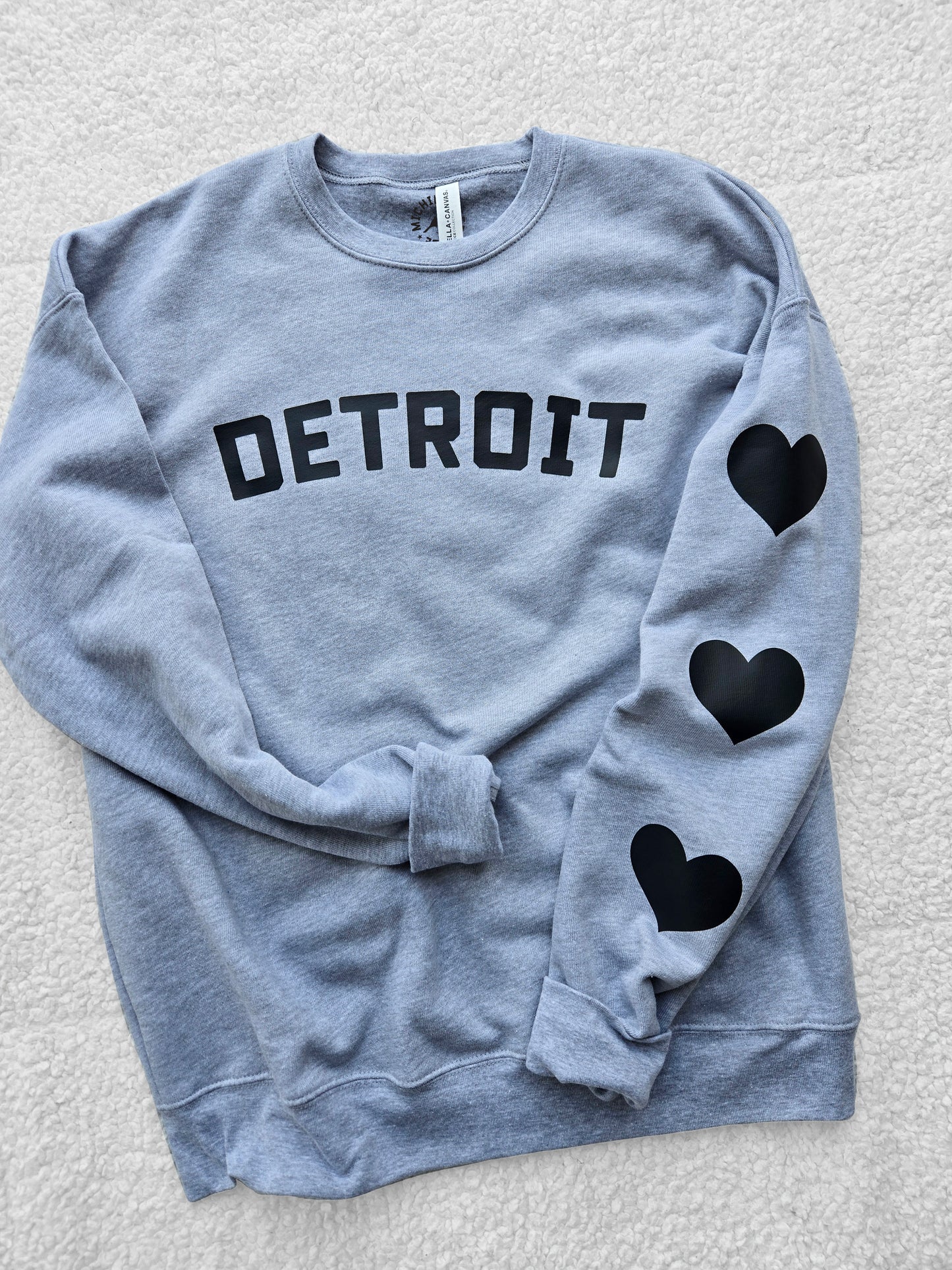 Detroit sweatshirt with black hearts. Fleece crew sweatshirt with Detroit logo and black hearts on the left sleeve.